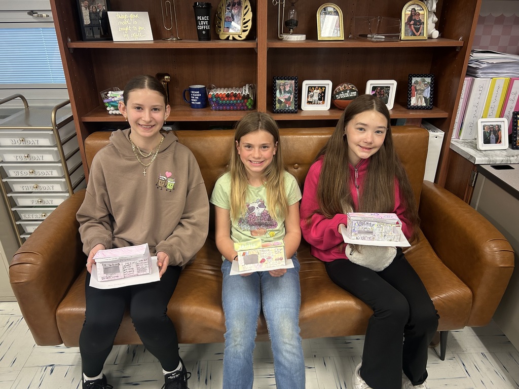Three students sit on a brown couch with their food trucks in their laps.