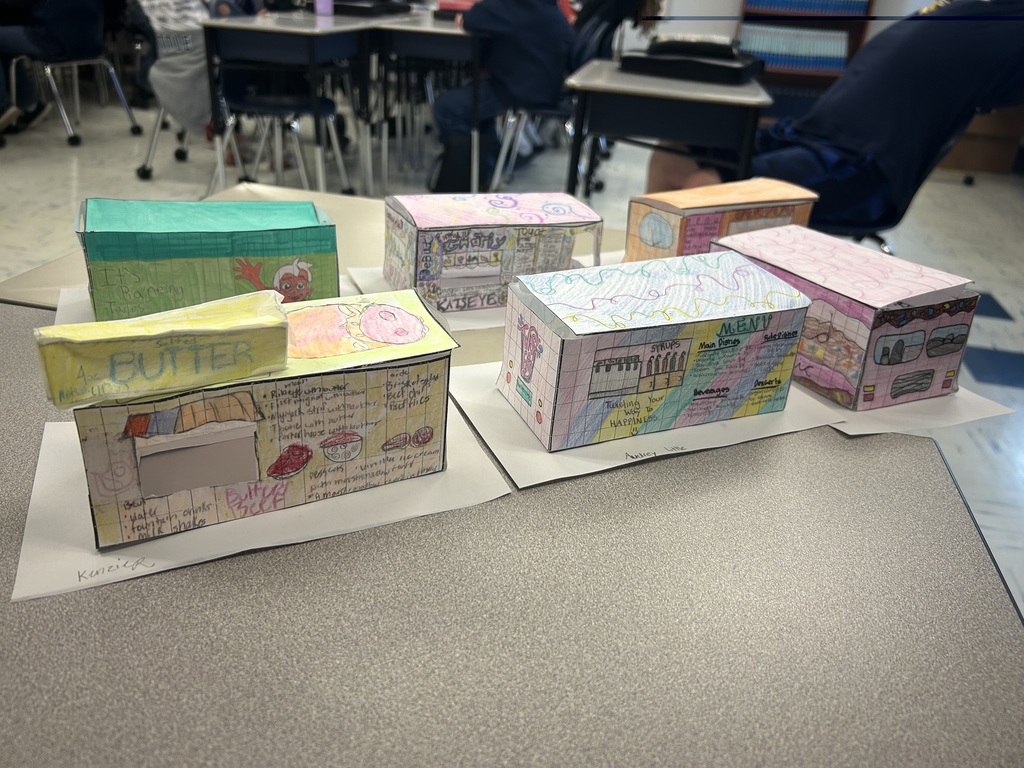 A close up shot of some of the food trucks, sitting on a desk with students in the background.