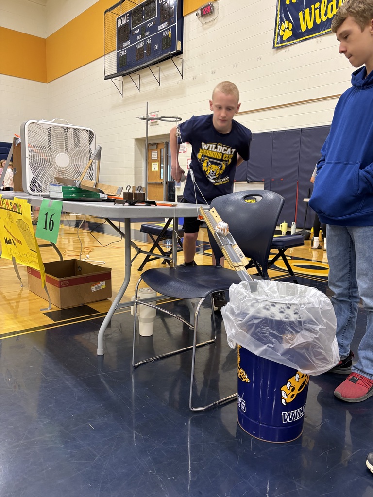 Two students watch their Rube Goldberg machine as it executes its different steps.