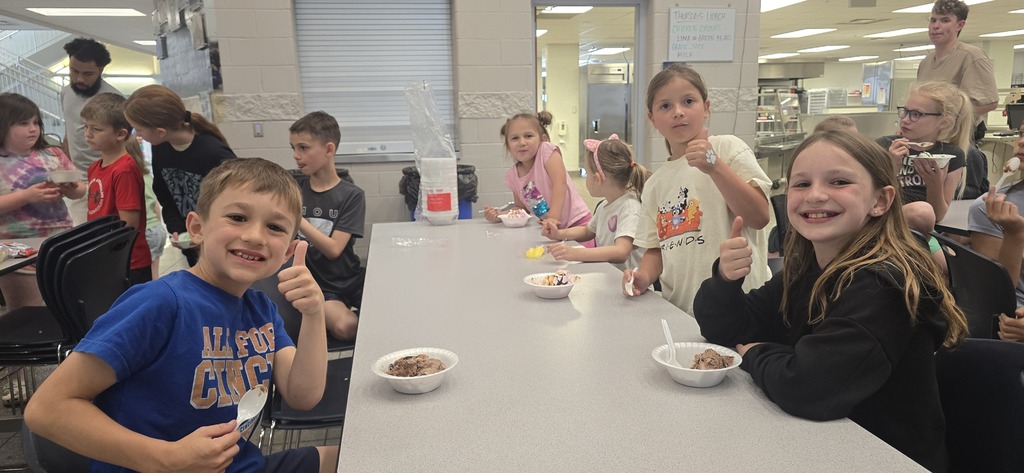 Students sit on either side of a table eating their ice creams