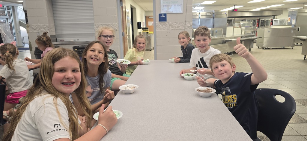 Students sit on either side of a table eating their ice creams