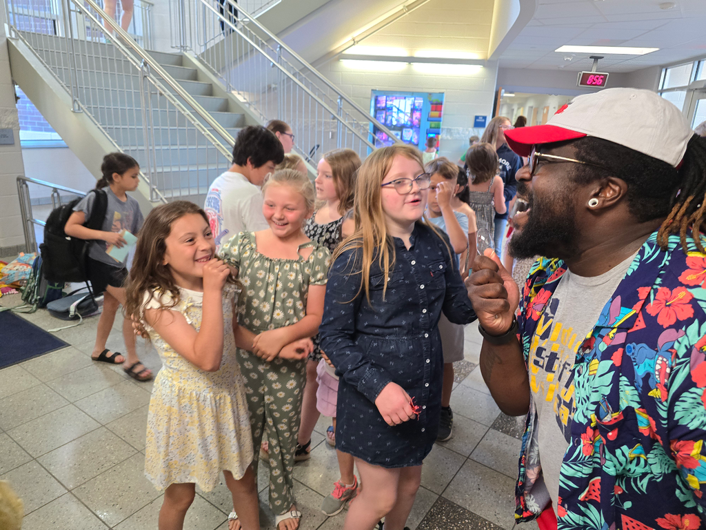 A teacher and elementary students sing into pretend microphones during the dance party in the lobby.
