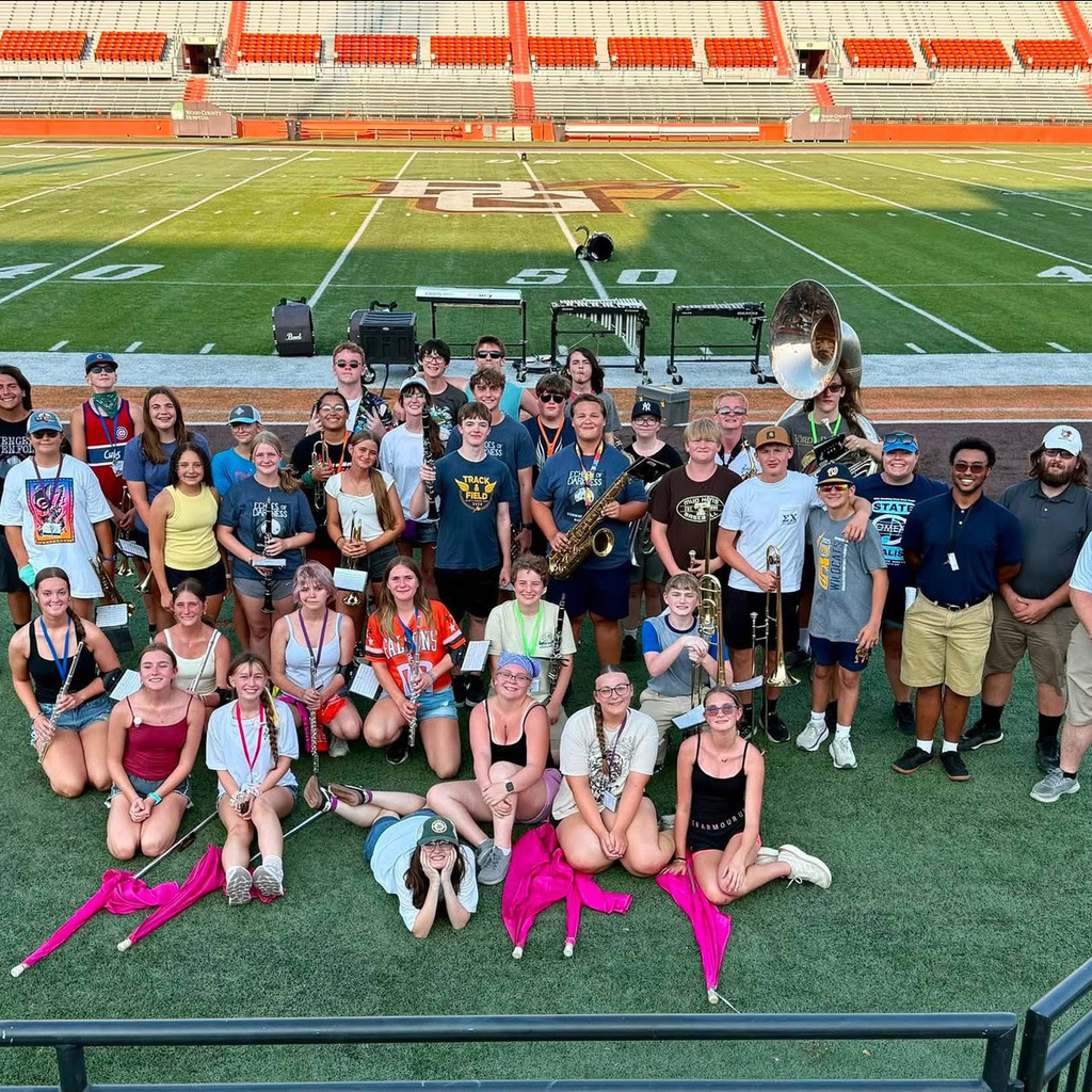 band student posing for a picture with their instruments during band camp at BGSU. They are standing on the football field.