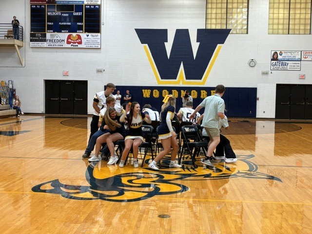 Many students are trying to find a seat while playing musical chairs in the middle of the gym floor.