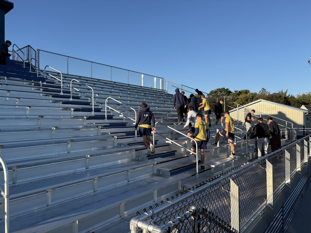 Football players cleaning up the stands. You can see the new barn in the background.