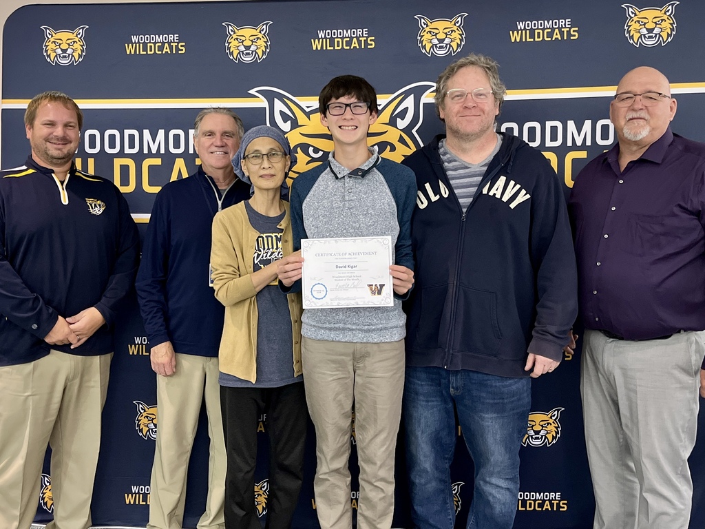 October High School Student of the Month, David Kigar, pictured with family and district representatives in front of the Woodmore backdrop.