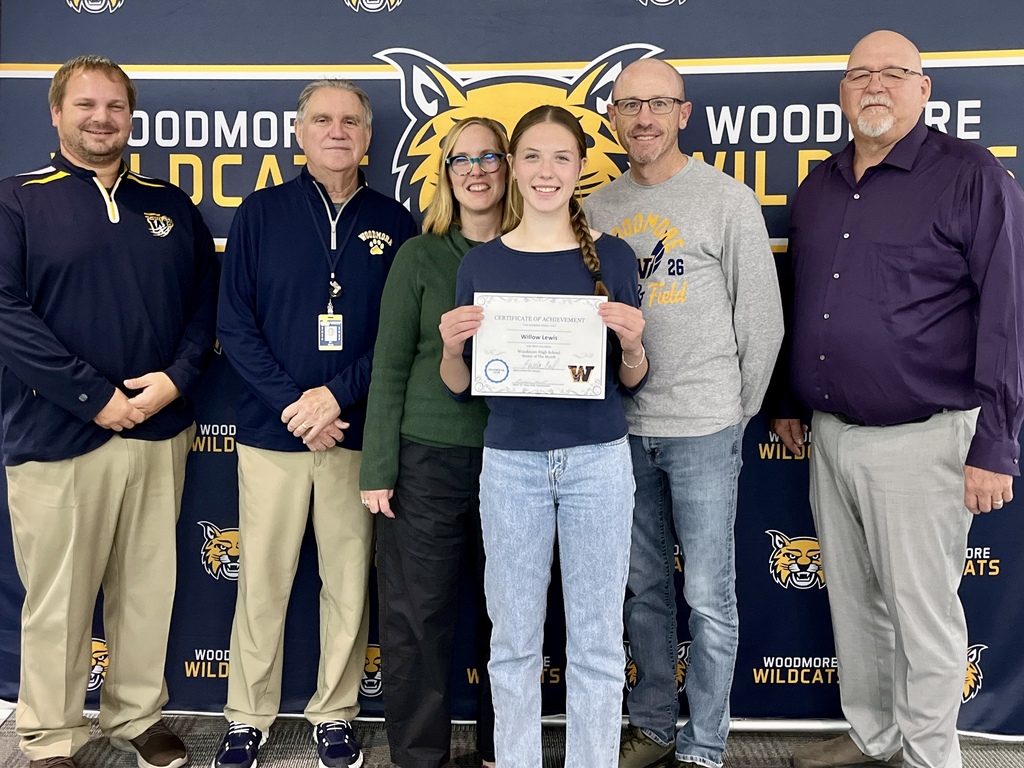 Willow Lewis, October Senior of the Month pictured with her family and district representatives in front of the Woodmore backdrop.