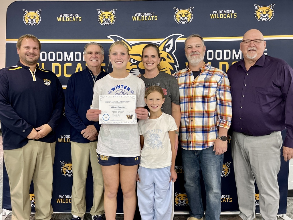 September Senior of the Month, pictured with family and district representatives in front of the Woodmore backdrop.