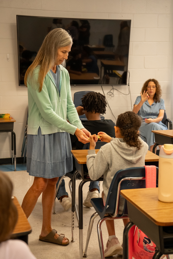 Teacher passing out things to students