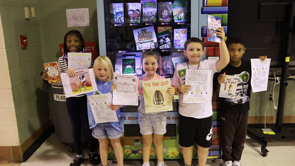 group of 5 students holding certificates by a book machine 