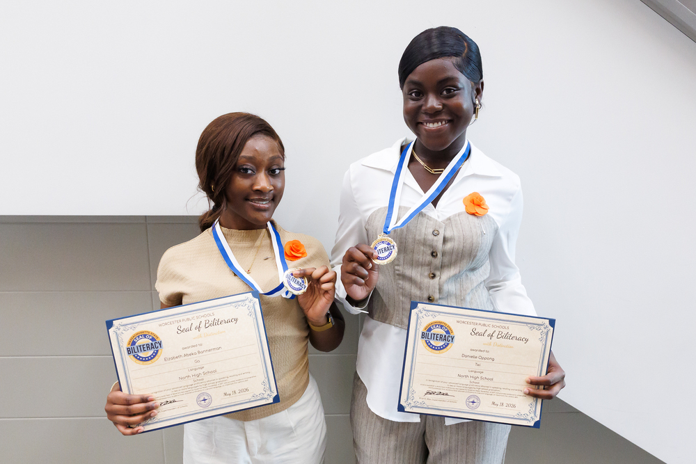 Two students hold their Seal of Biliteracy certificates and medals following a celebration ceremony.