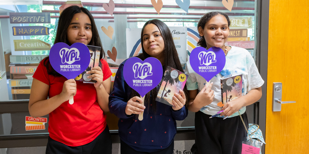 From left, Jaydaliz Crespo, Julia Neves Pessoa, Lexismarih Carrion of Dr. Arthur F Sullivan Middle School hold up free copies of their summer reading books, provided by Worcester Public Library during a school visit on Tuesday, June 3, 2025. 