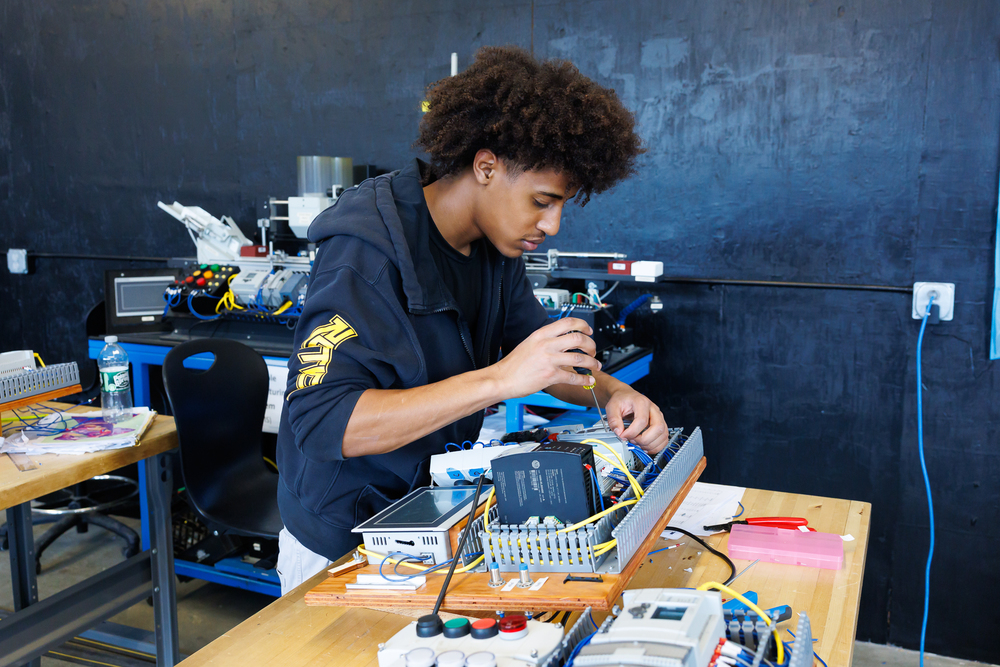 A student uses a screwdriver to work on robotics equipment