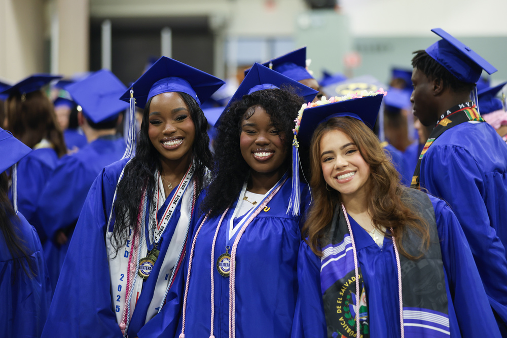 Three students wearing caps and gowns