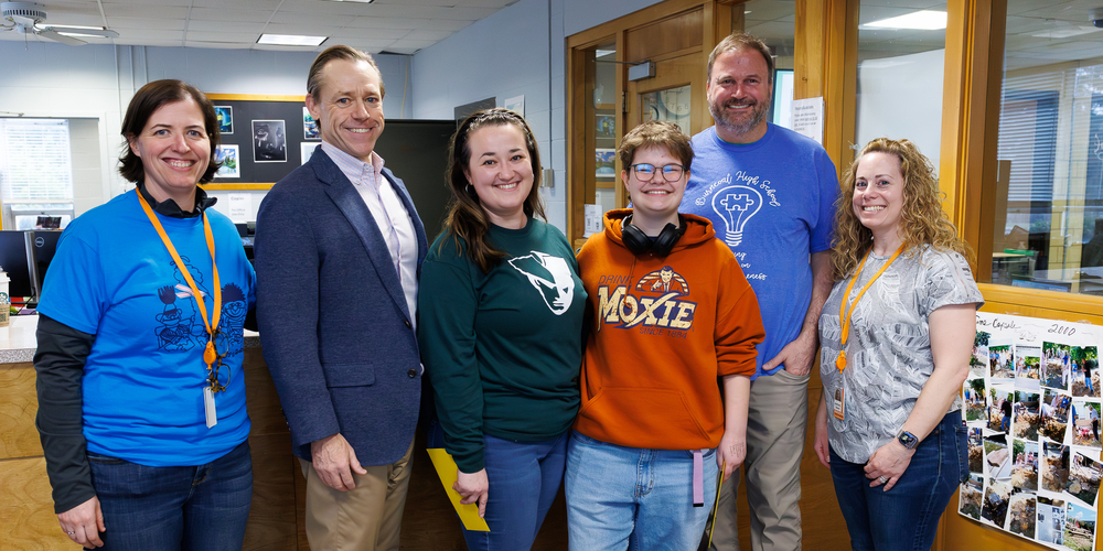 Five adults and one student stand together and smile.