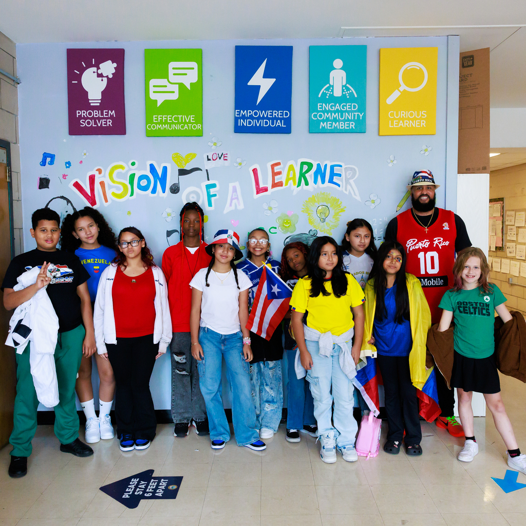 A large group of students in cultural attire stand with Principal Ish Tabales.