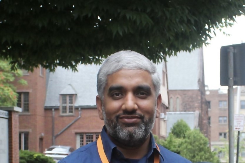 A man with a beard and gray hair smiles at the camera.