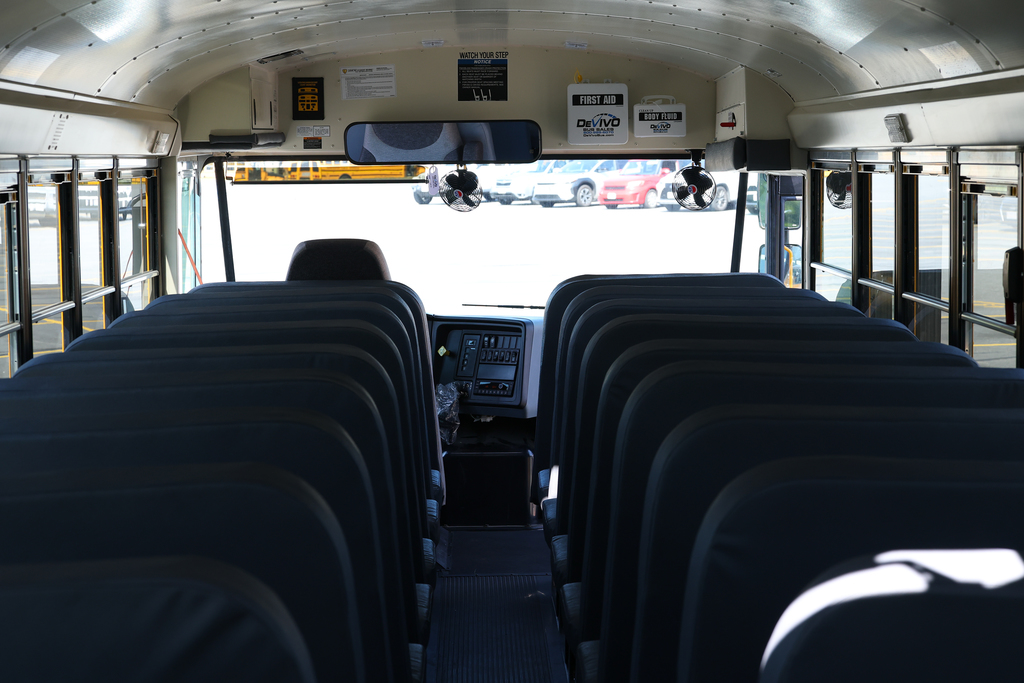 Interior view of an empty school bus, with rows of seats facing forward.