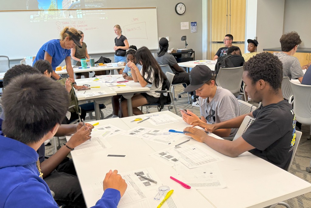 Students work on a project at tables in a classroom setting.