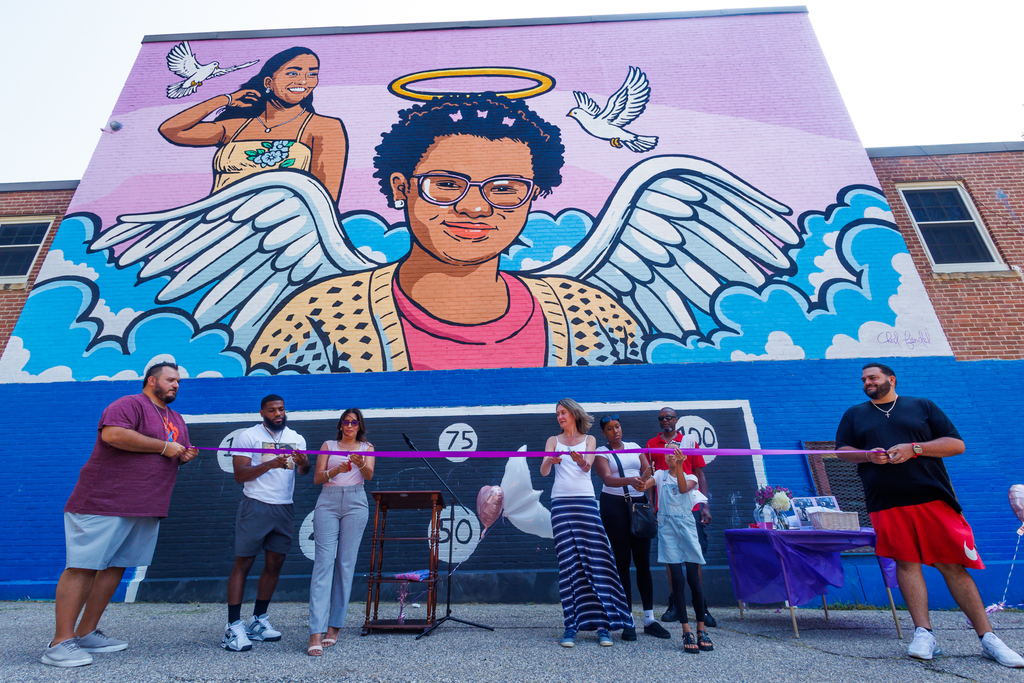 Family members of Zella & Chasity Nunez, alongside muralist Chad Fandel, cut the ribbon the new mural at Columbus Park.