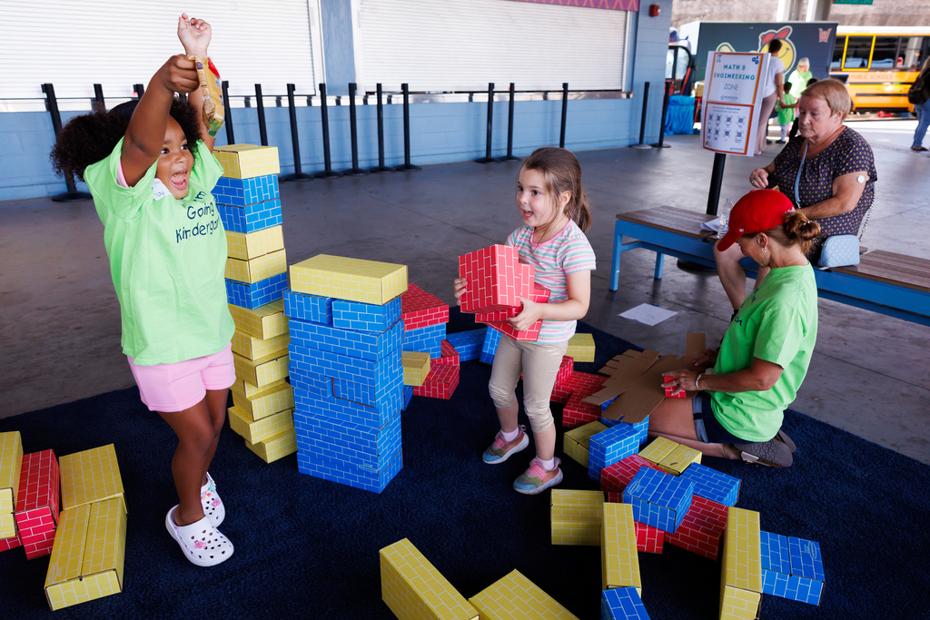 Children play with large building blocks, constructing towers and structures.