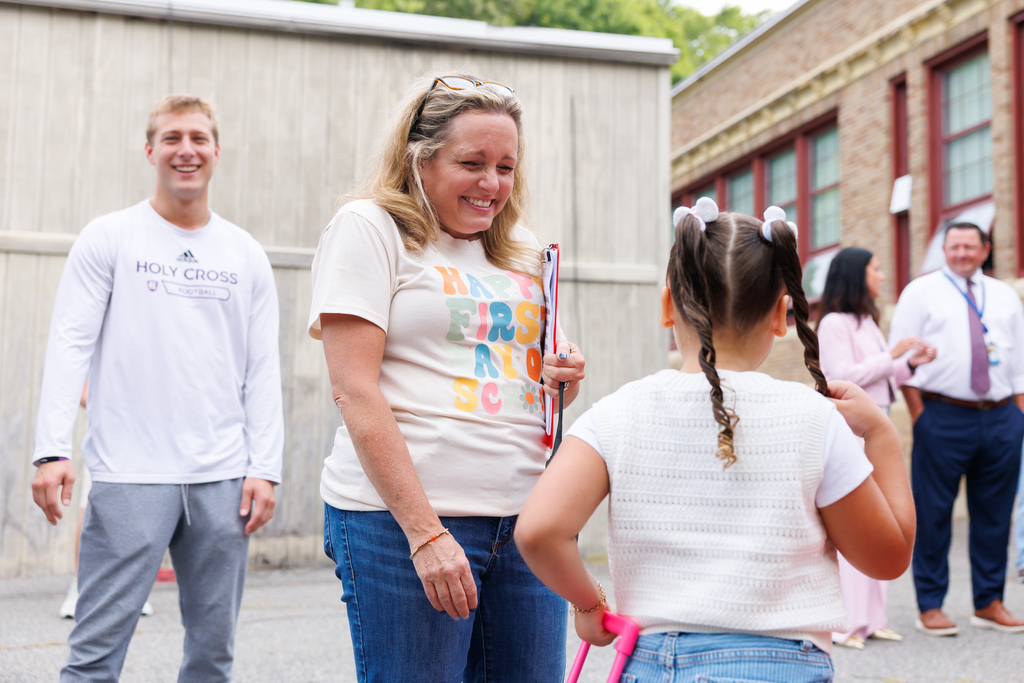 A teacher smiles with a student on the first day of school.