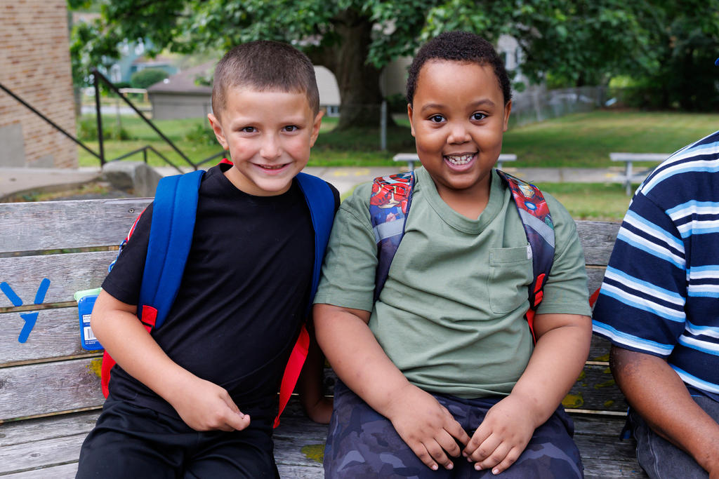 Two students sit together for a photo, both smiling, on the first day of school.