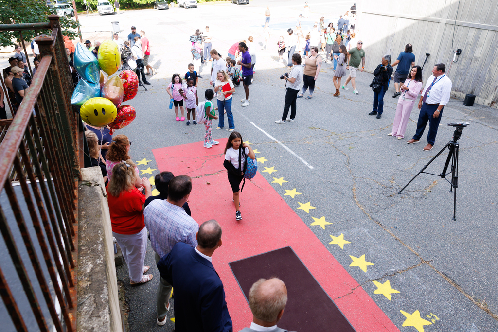 A student walks the red carpet while entering school on the first day.