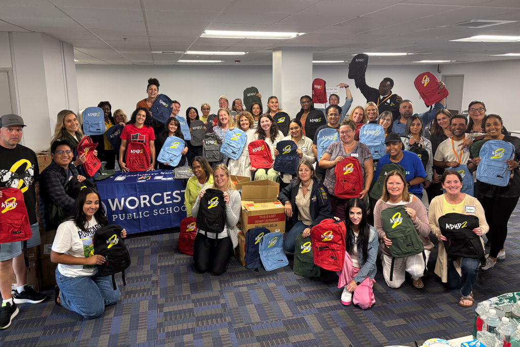 WPS Wraparound Coordinators hold up donated backpacks that say "ADHD 2". 