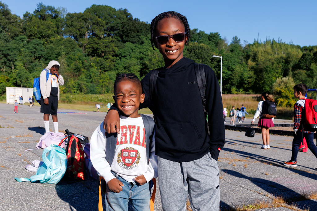 Two brothers stand for a photo, smiling, on the first day of school.