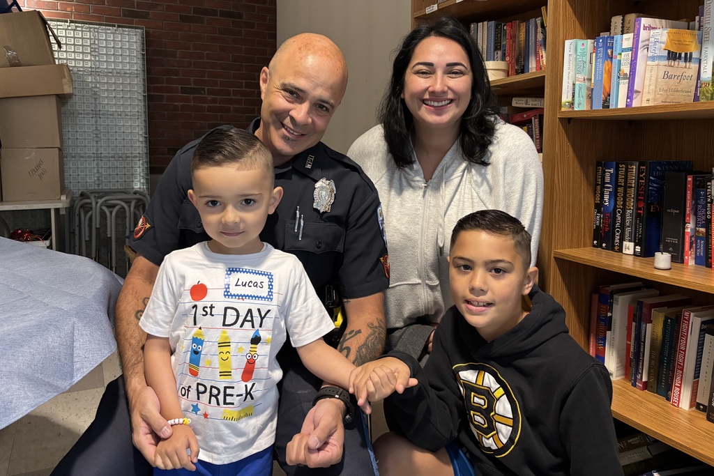 A family of four take a photo together, one child is wearing a shirt that says "1st Day of Pre-K"