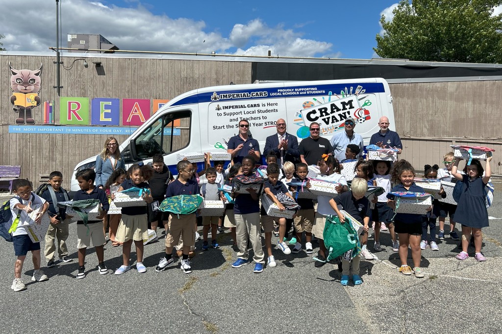 Children and adults pose with boxes in front of a van that says 'Cram Van!'