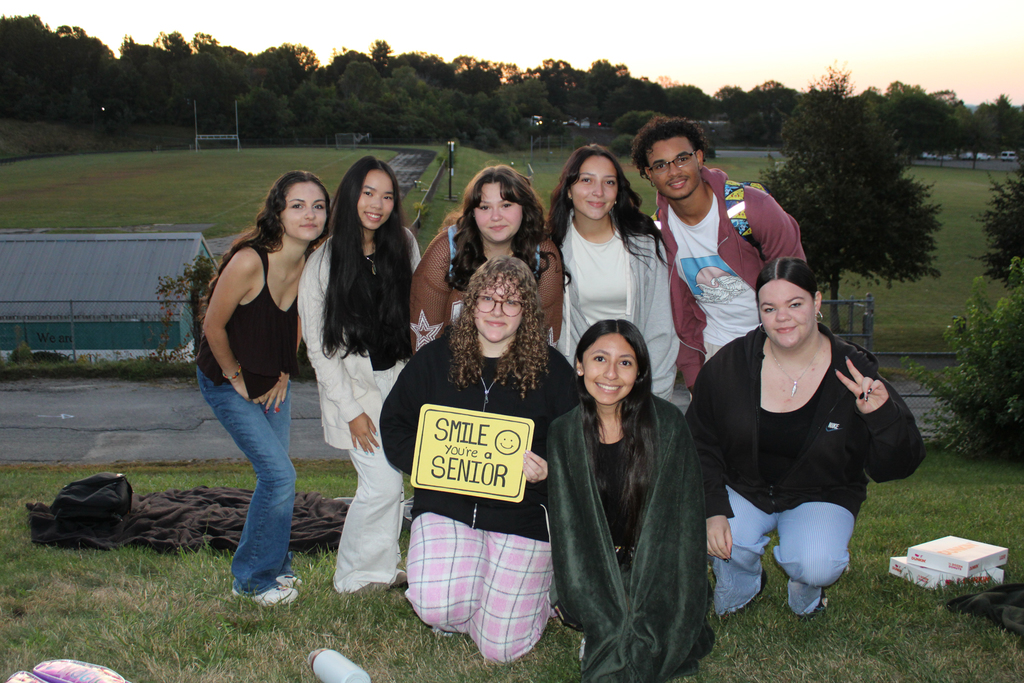 A group of friends pose for a photo outdoors, smiling at the camera.