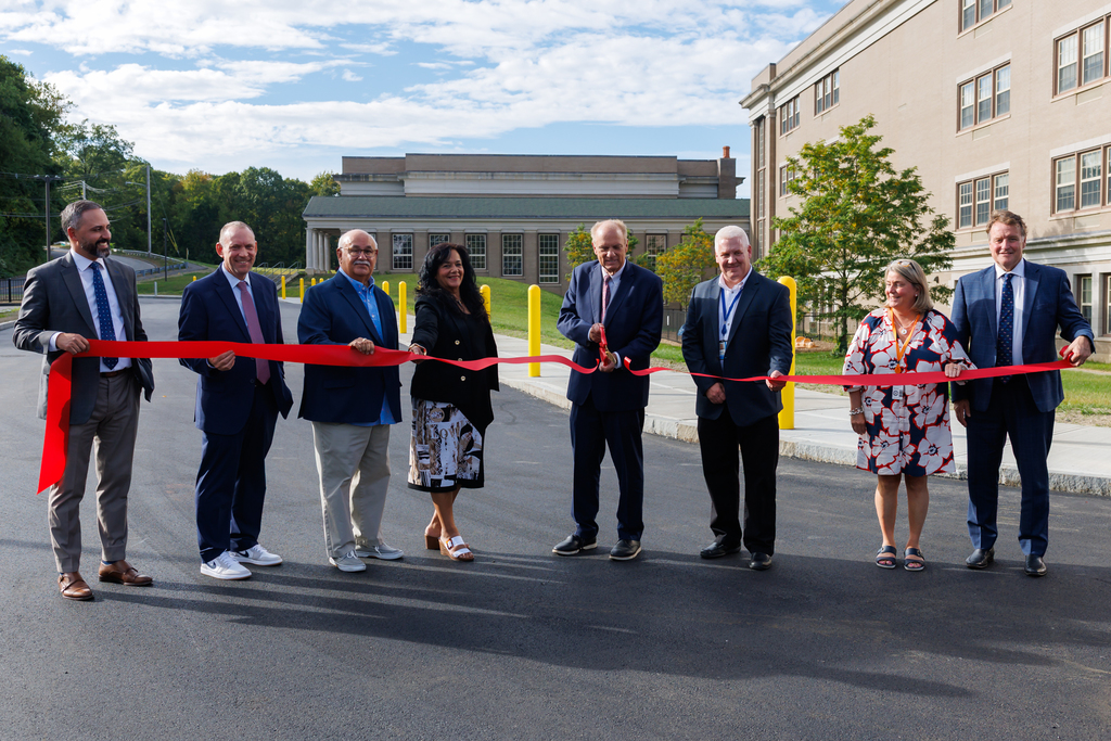 Worcester City Officials prepare to cut a red ribbon outdoors.