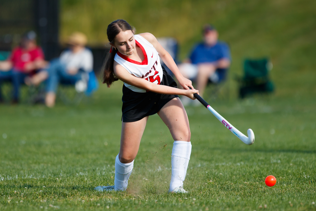 A student hits the ball during a field hockey game.
