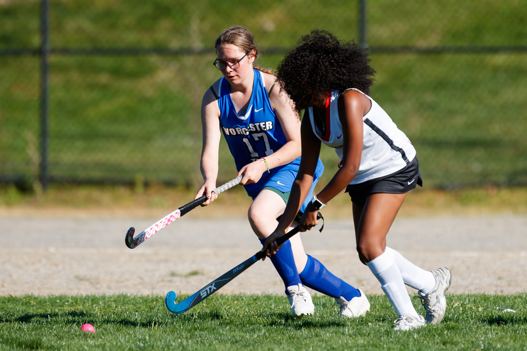 Two students go after the ball during a field hockey game.