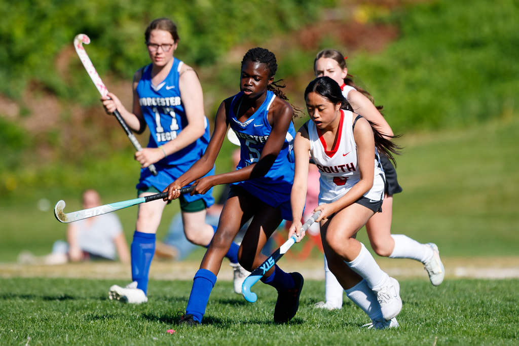 Two players go after the ball during a field hockey game.