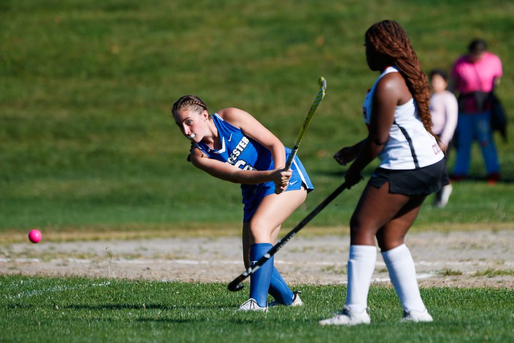 A student hits the ball during a field hockey game.