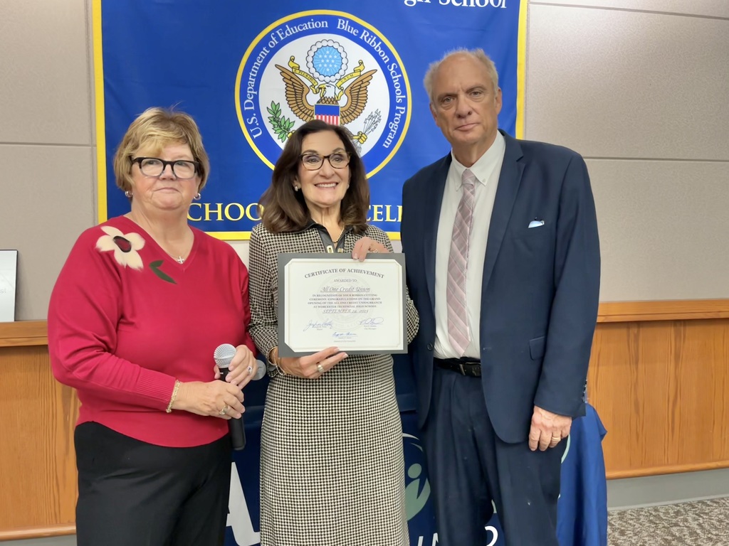 A bank official holds a certificate with two elected officials standing beside her