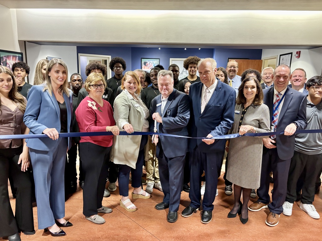 A bank official cuts a ceremonial ribbon in front of a large group of people