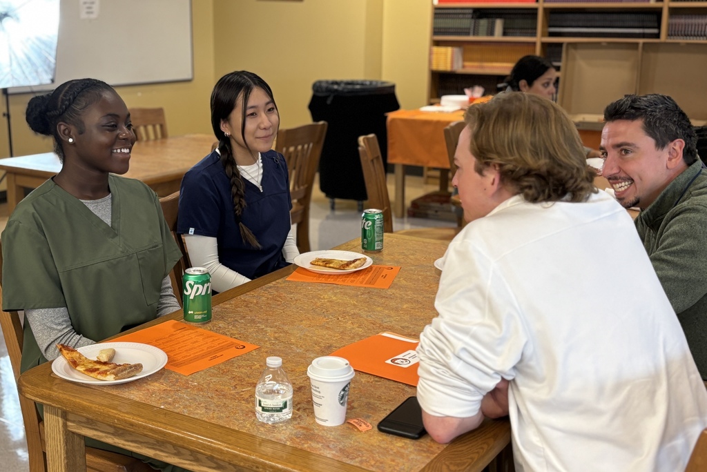 A group of people sit around a table, smiling and talking.