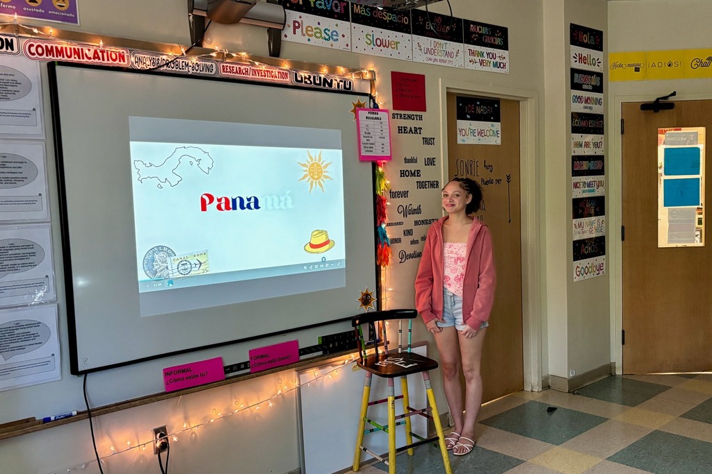 A student stands in a classroom, presenting a slide about Panama.