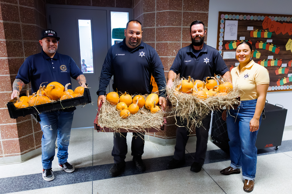 Staff from the Worcester County Sheriffs Office hold up baskets of pumpkins.
