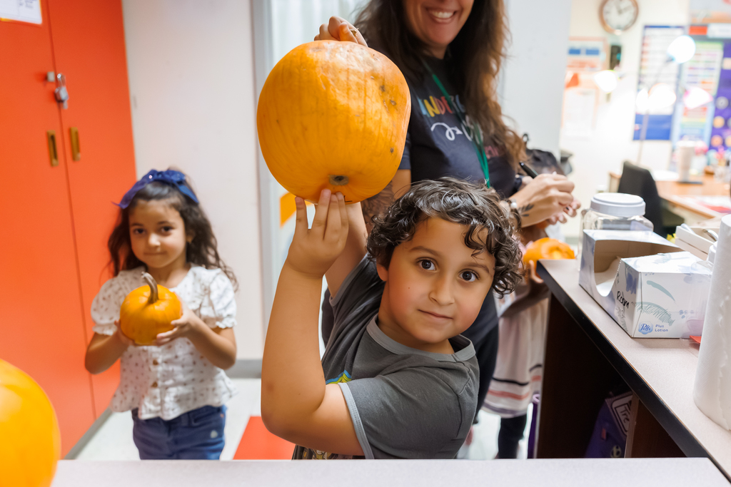 A student holds up their pumpkin.