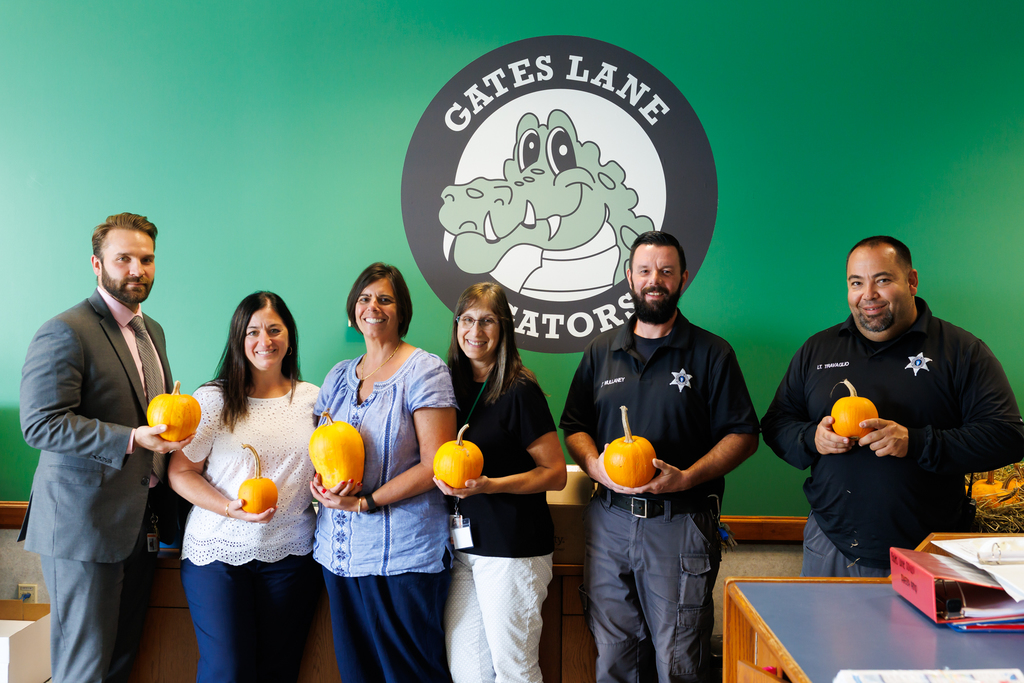 Staff from Gates Lane, alongside members of the Sheriff's office, hold up pumpkins.