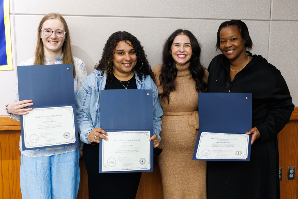 A teacher and adult night life students hold up a certificate of completion.