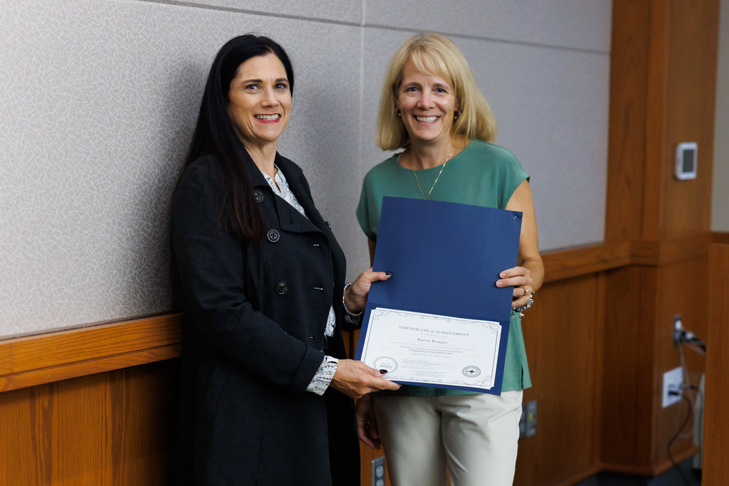 An instructor and adult night life student hold up a certificate of completion.