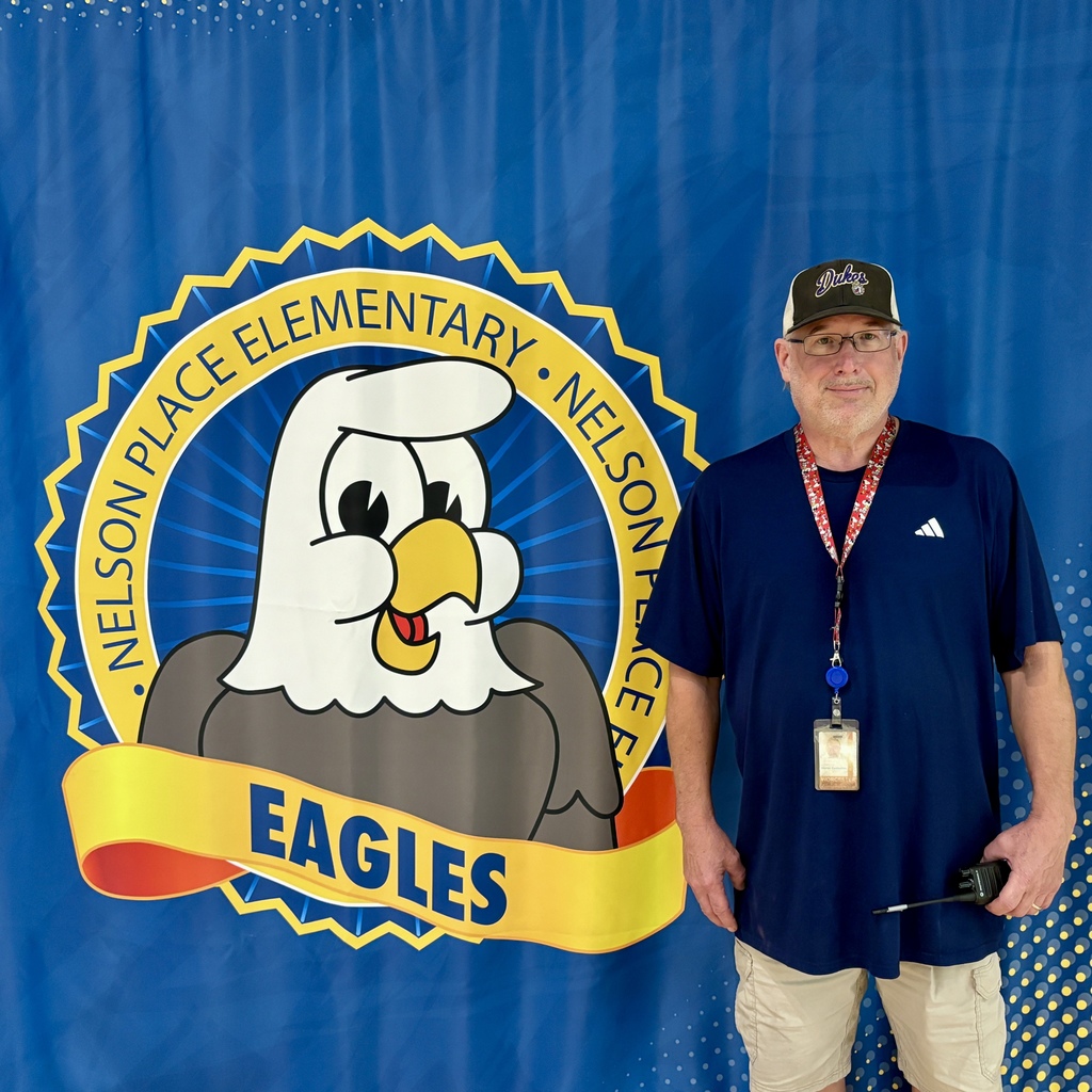 A man stands in front of a blue banner with a school logo and the word 'Eagles'.