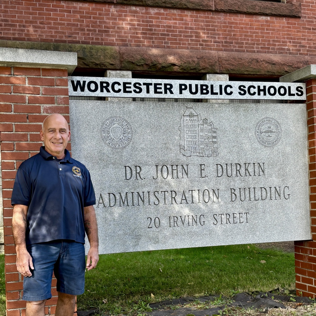 A man stands in front of a sign for the Worcester Public Schools Administration Building.