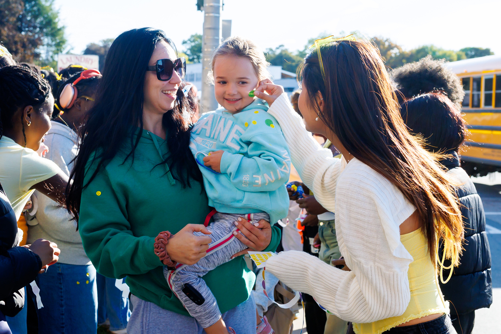 A South High student puts a Smiley Face sticker on the cheek of a young child.